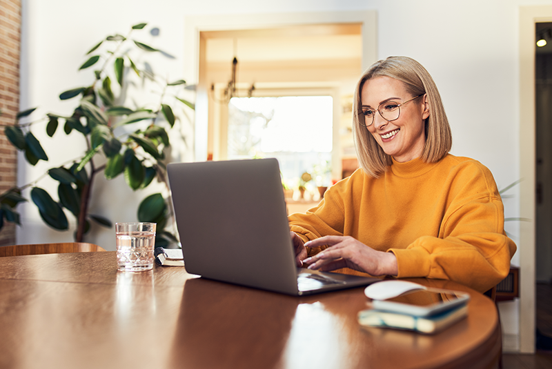woman typing on laptop in orange shirt